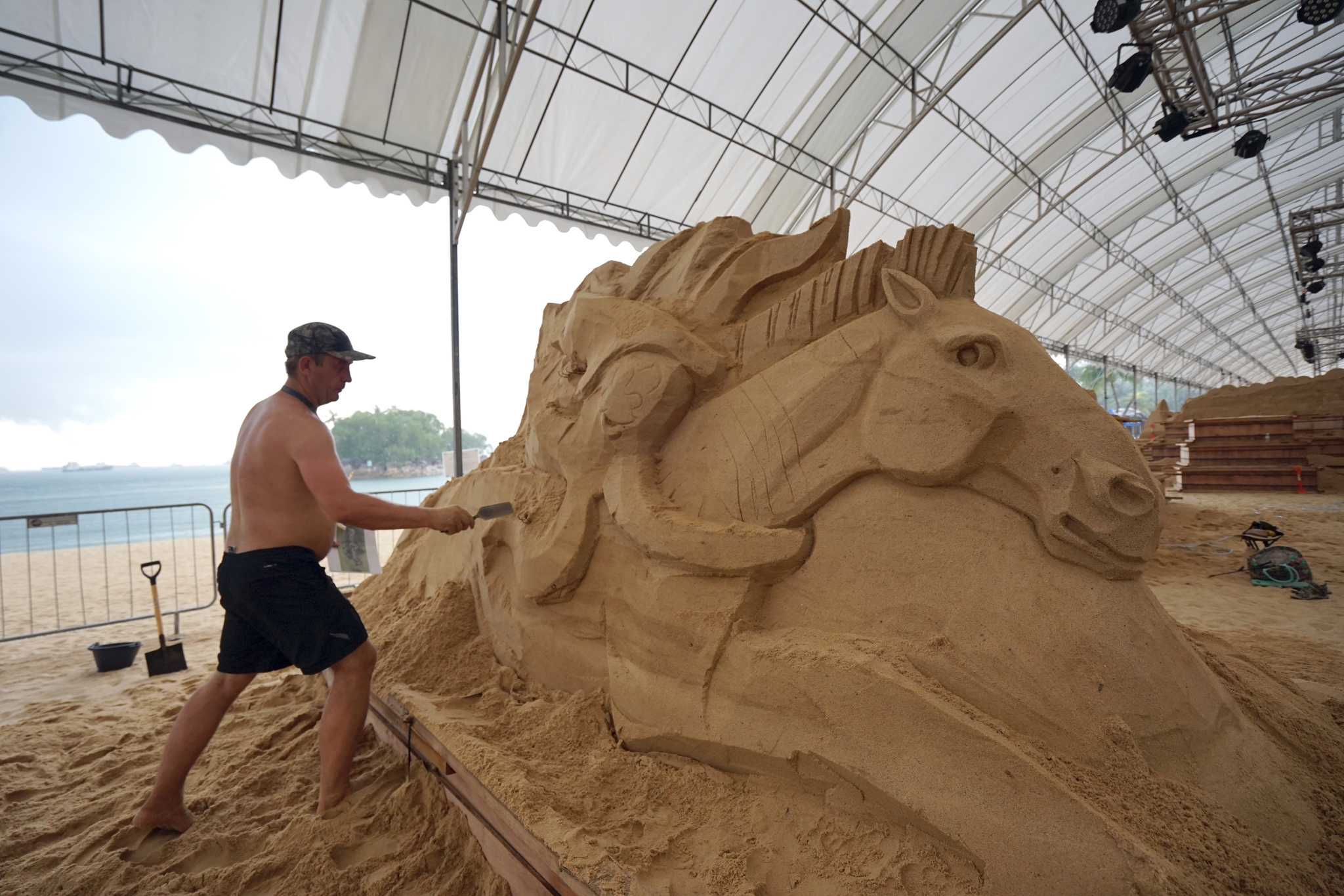 Artists giving final touches to the sand sculptor on Siloso Beach in Singapore.