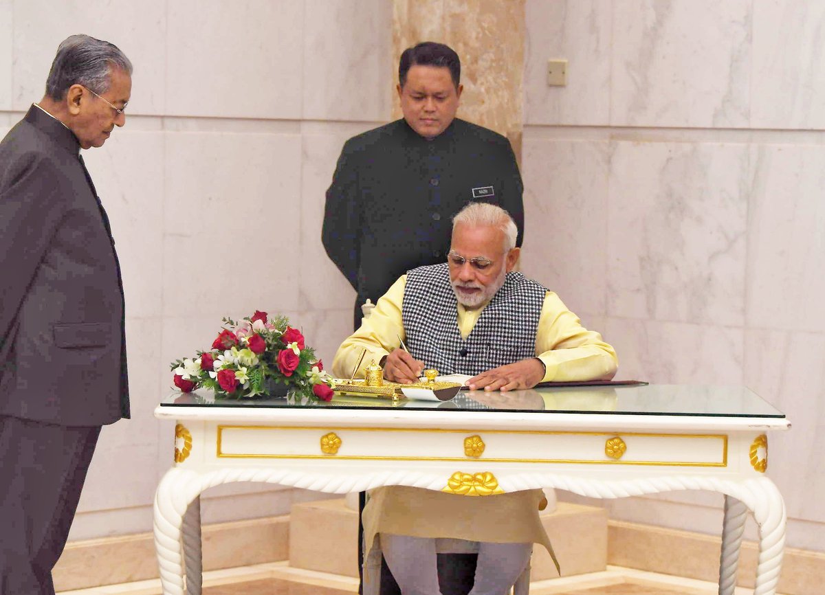 Indian Prime Minister Narendra Modi signing a document in presence of Malaysian Prime Minister Mahathir Mohammad in Kuala Lumpur.