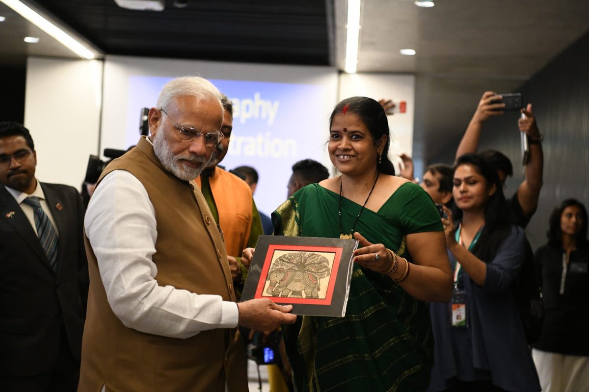 An Indian artist showing her painting to PM Modi at Indian Heritage Centre. 