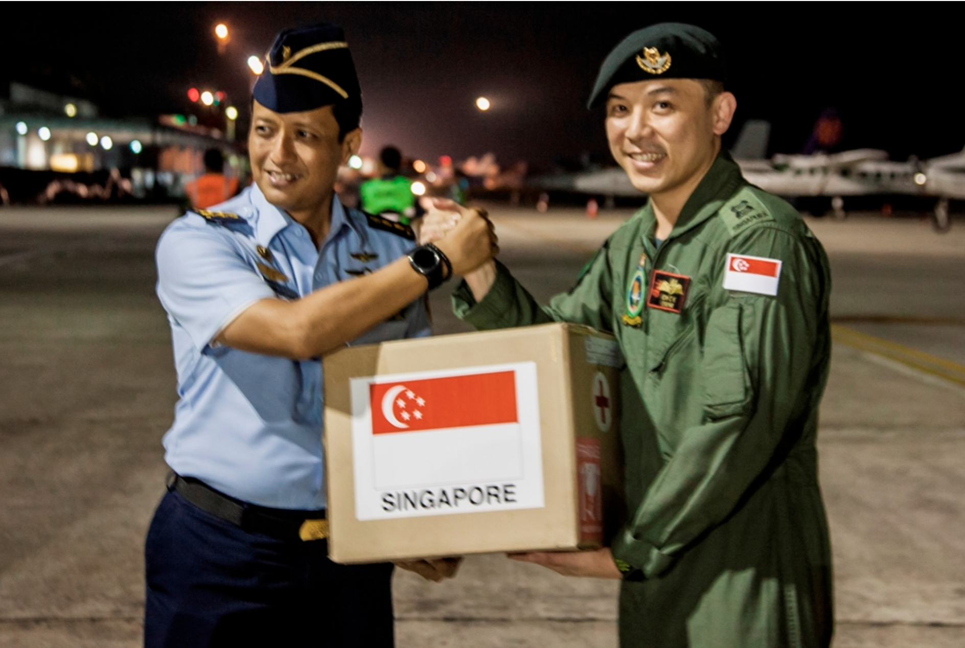 The Singapore Armed Forces Mission Commander, Lieutenant Colonel (LTC) Oh Chun Keong (right) handing over the relief package to LTC Ali Sudibyo, of the Indonesian Armed Forces (left) at Balikpapan Airport, Indonesia. Photo courtesy: Mindef
